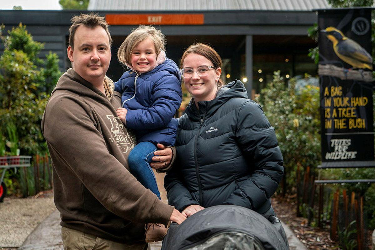 A man a woman and a toddler posing for the camera with a pram