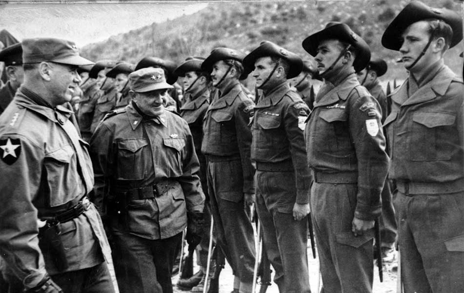 Two generals inspect a line of soldiers in slouch hats standing at attention