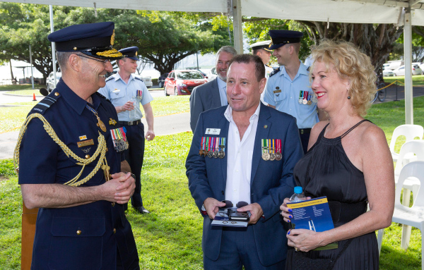 A man in Air Marshal's dress uniform chats with a man and woman in a marquee.