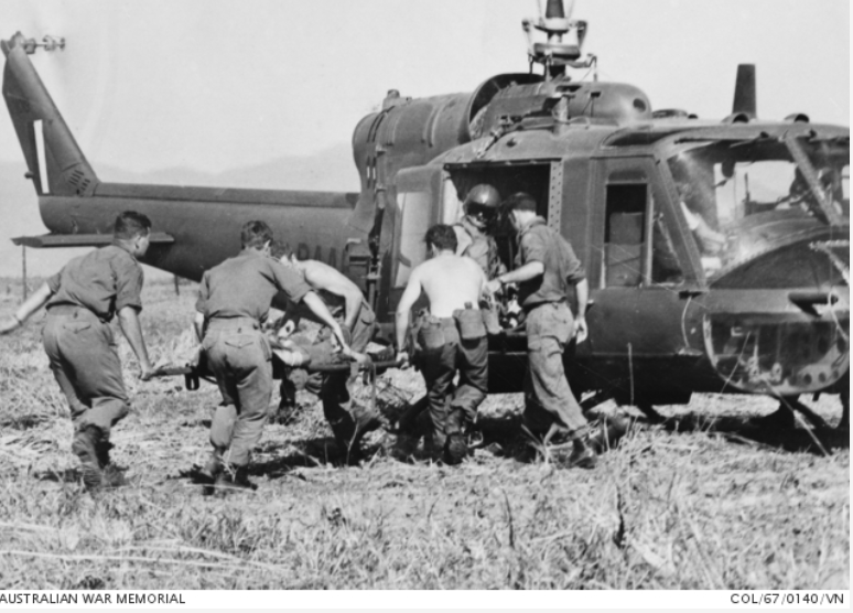 Five soldiers help get a man on a stretcher aboard a helicopter