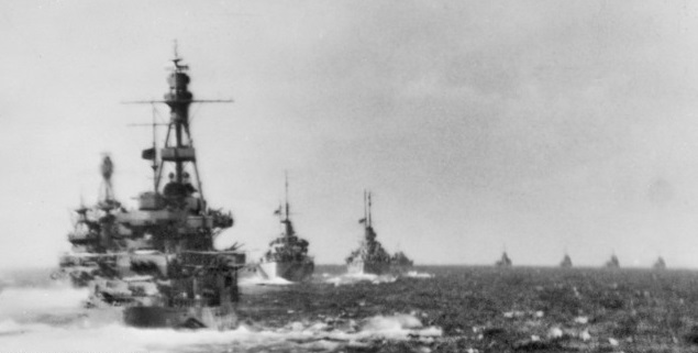 Warships in foreground with four other ships on the horizon