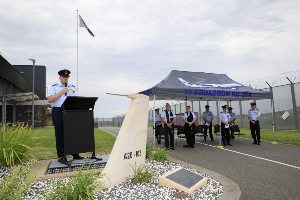 RAAF officer gives speech next to marquee with more RAAF personnel inside
