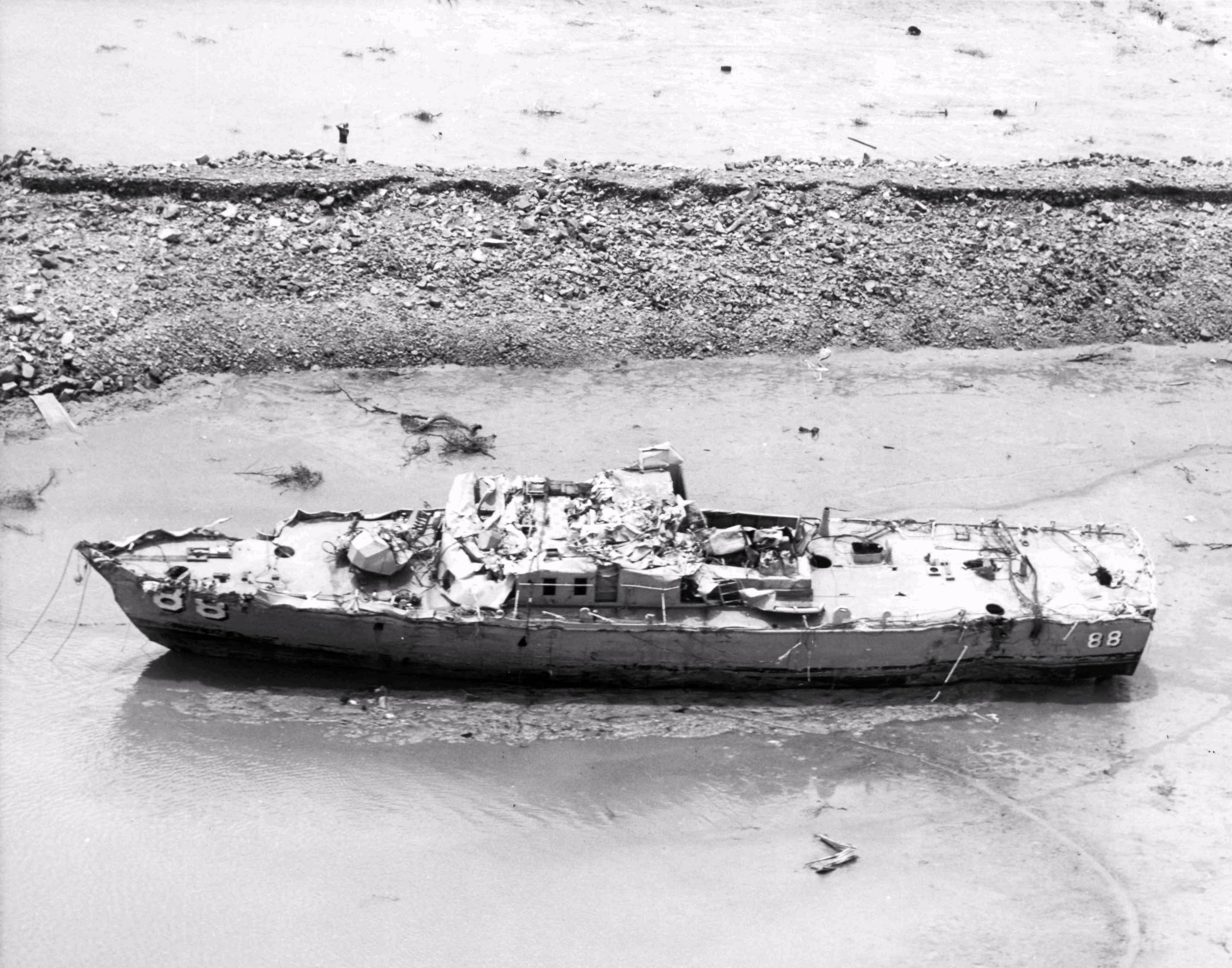 A badly damaged patrol ship in the shallows of a beach