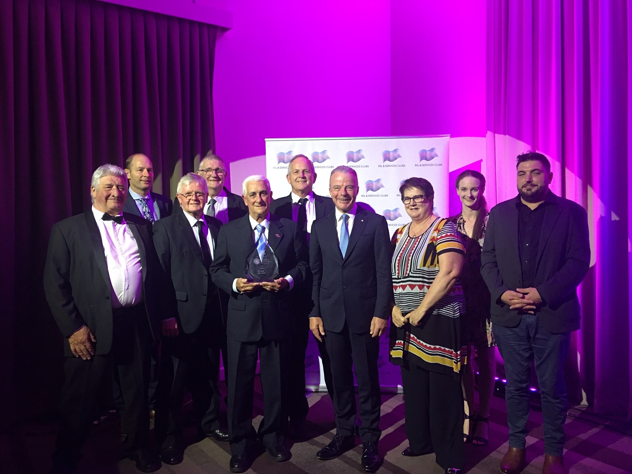 Ten people posing for camera at awards event.