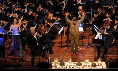 Conductor in khaki surrounded by an orchestra