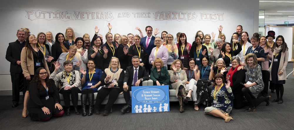 Group of about 40 women and three men posing for camera in office