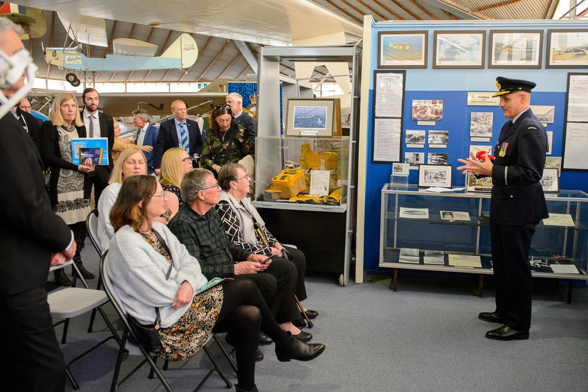 Air Commodore addresses about a dozen people in an aircraft museum