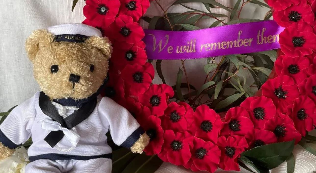 Teddy bear in sailor uniform next to wreath