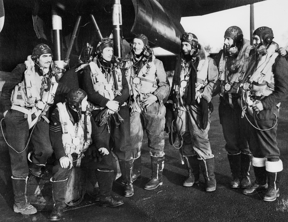 A group of RAAF members standing beneath a Lancaster Bomber.