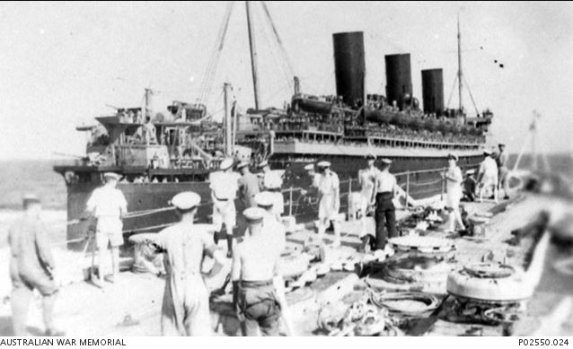 The Queen Mary, a British ocean liner, steams alongside the smaller Kent class cruiser HMAS Canberra, in the Atlantic during the Second World War. Some of the crew are on deck watching the Queen Mary sail past.