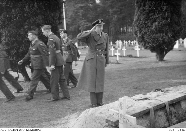 Young RAF officer salutes near grave