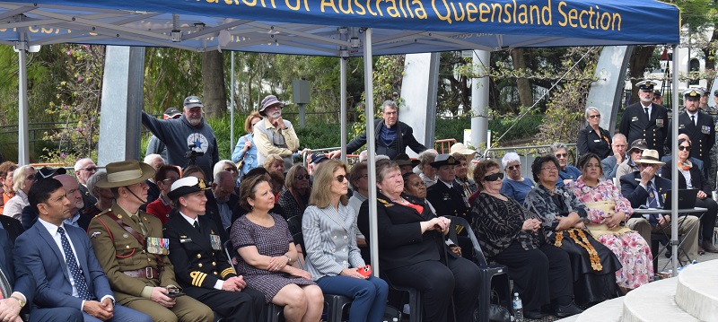 About thirty people, some in uniform, under a marquee