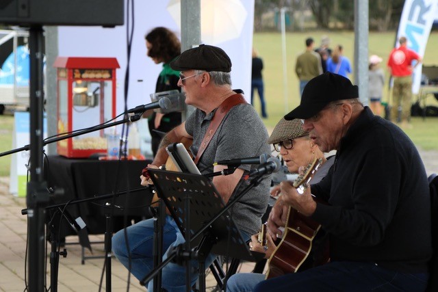 Three older men playing the guitar outside