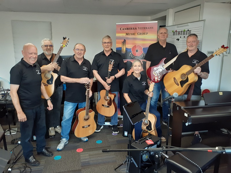 Seven people posing for camera holding guitars