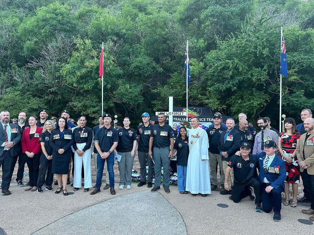 About thirty people standing in front of Australian and Timor-Leste flags at a memorial