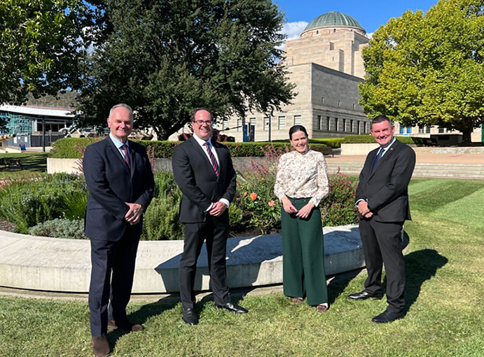 Four people stand in front of a garden.