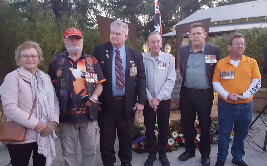 One woman and five men pose for photo. Most are wearing medals.