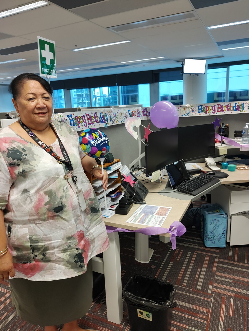 Smiling woman standing next to desk covered in farewell messaging