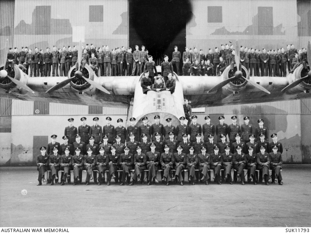 Black and white photo of about sixty air force personnel posing on and in front of a large aircraft