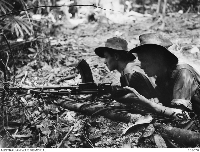 Two young soldiers man a Bren gun in jungle conditions