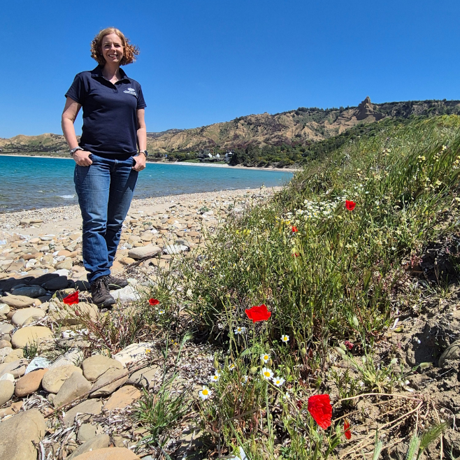 Woman in jeans and DVA T-shirt standing on beach
