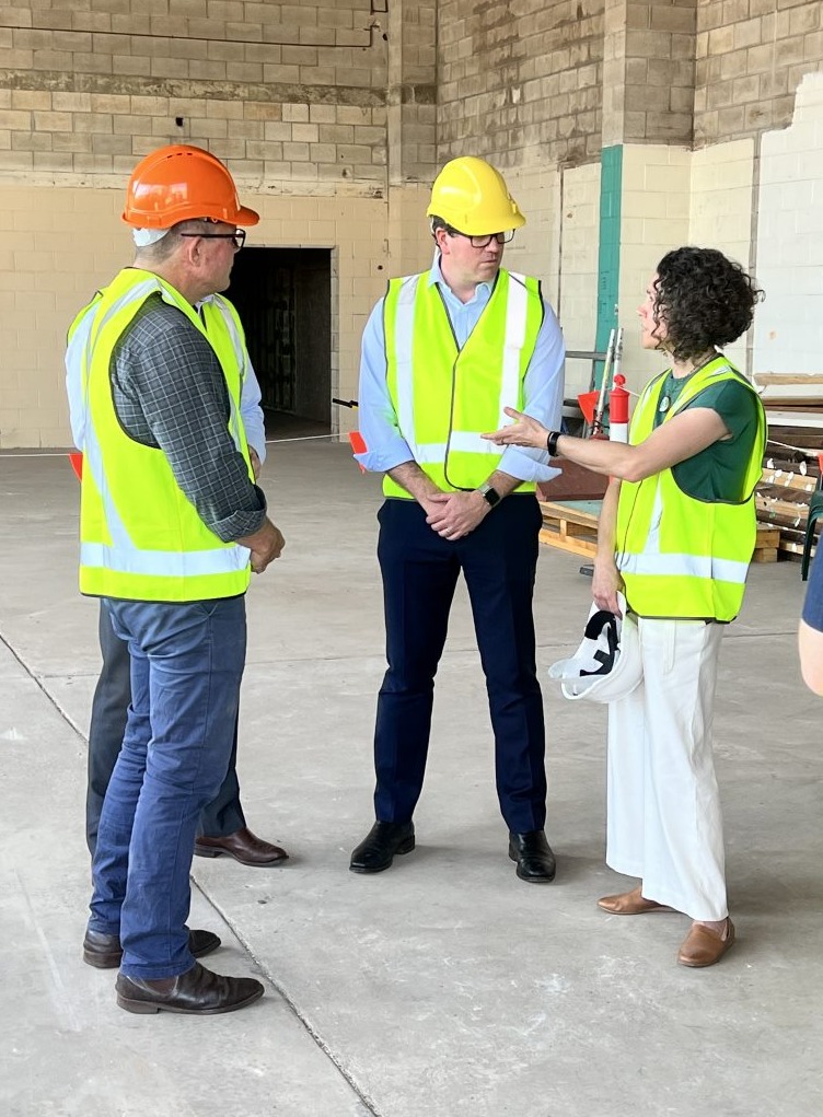 Minister standing with colleagues wearing hard hat
