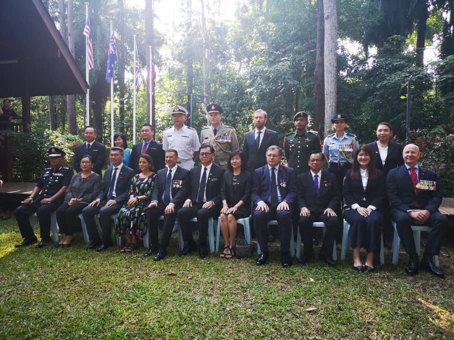 About twenty people posing for group photo outside a pavilion in the jungle