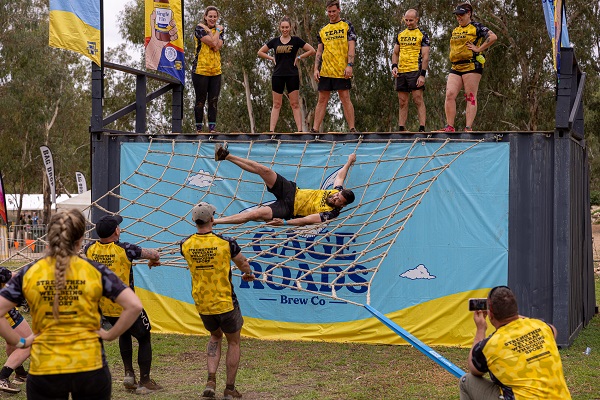 Several people watch someone deal with part of an obstacle course