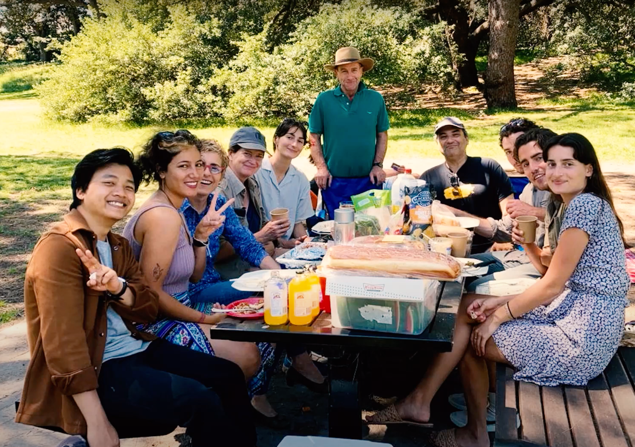 10 people gathered around picnic table