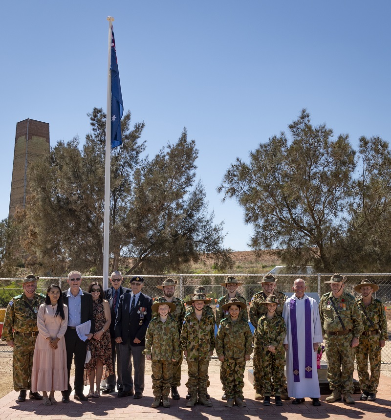 A large group of people posing for a photo in front of a commemorative area
