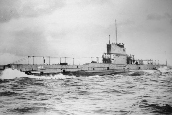 Black and white photo of submarine at sea with sailors on casing