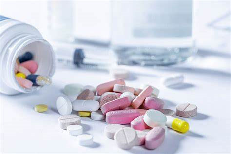 Colourful medical pills spilling out of the white container