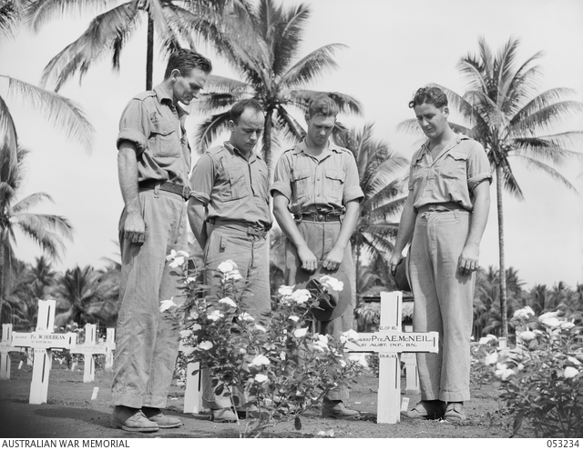 A black and white photo of Australian soldiers standing in memory of a fallen friend's grave.