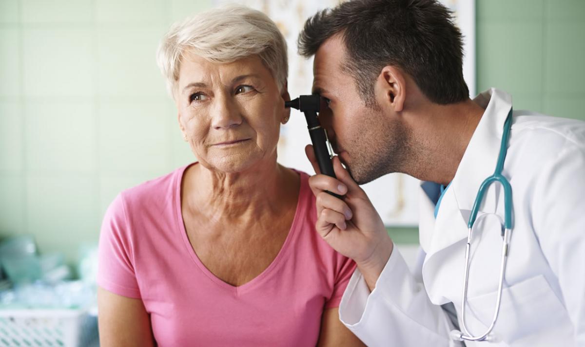 Doctor peering into ear of patient