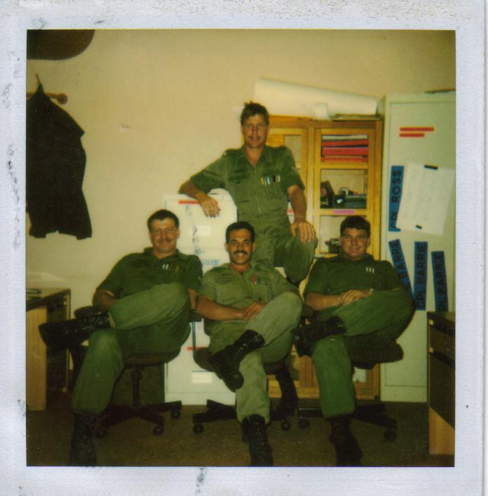 Old colour photo of young man in Army uniform posing with three colleagues