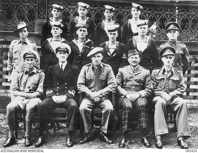 Formal black and white photo of 15 men in various uniforms.
