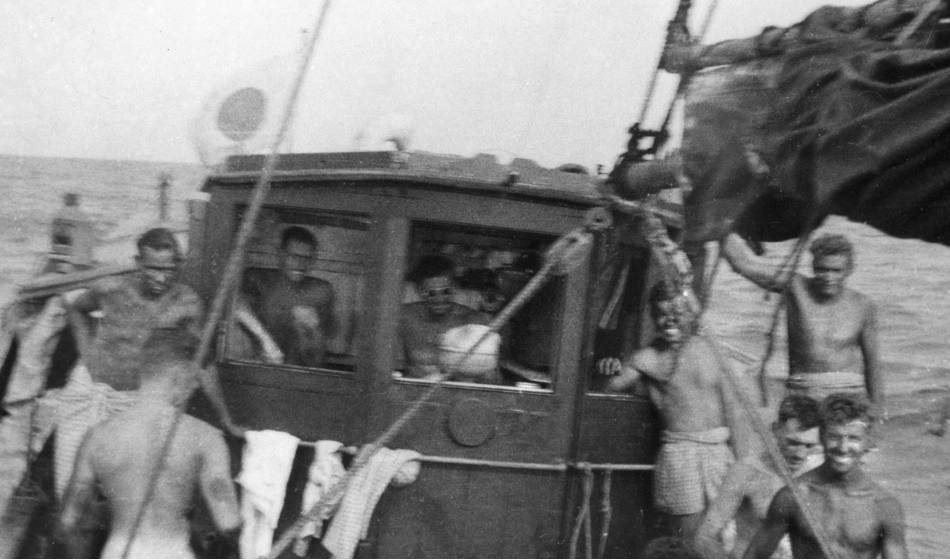 Fuzzy photo taken from the prow of the sampan looking aft. Most of the eight men visible are smiling.
