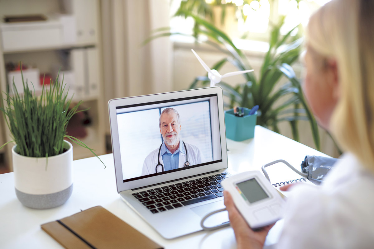 A woman using a laptop computer to listen to a male doctor.