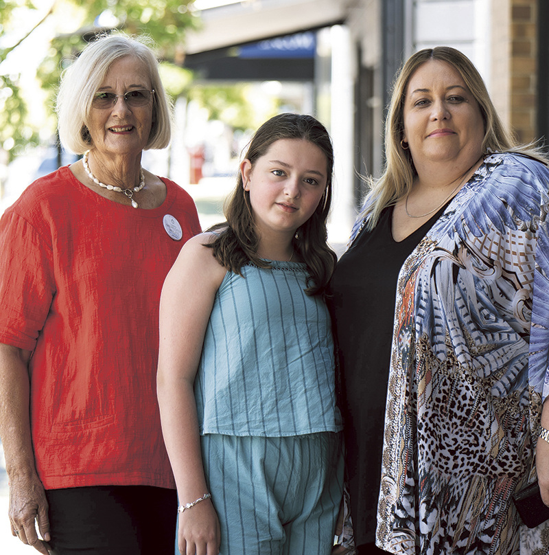 An older woman, a middle-aged woman and a girl pose for the camera.