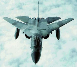 Front view of an F-111 jet fighter flying over clouds.