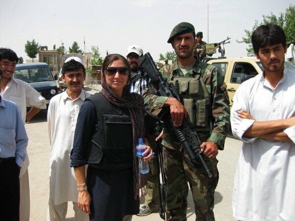Caucasian woman posing among handful of Afghan men.