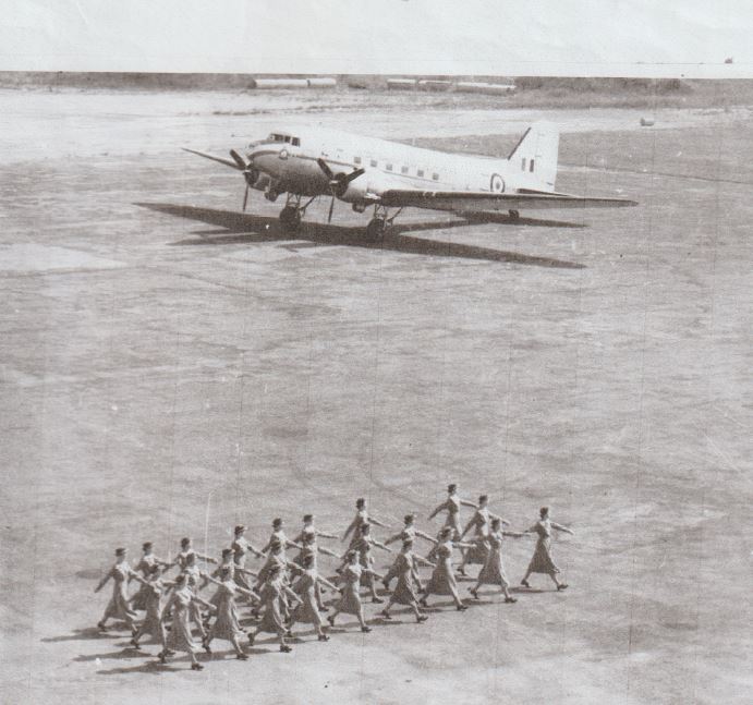Young women marching near plane on tarmac