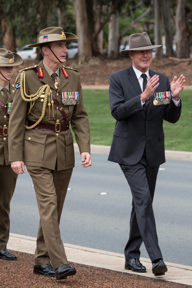 Man in suit walking alongside man in a General's uniform