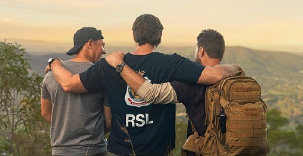 Three young men with backs turned with arms round each other, one wearing RSL T-shirt
