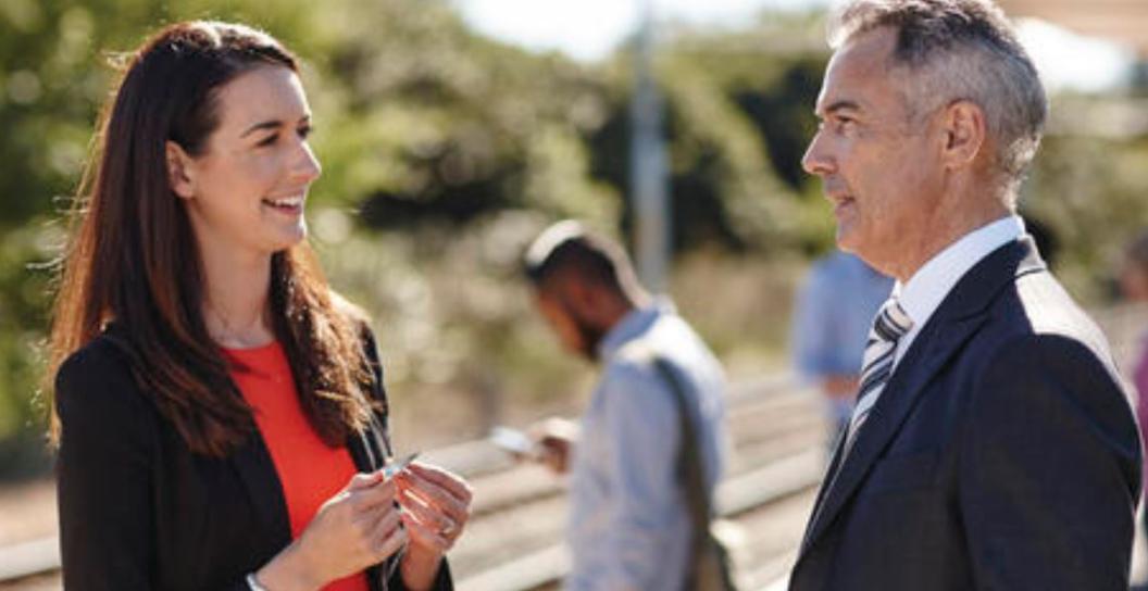 A man and a woman chat on a train platform