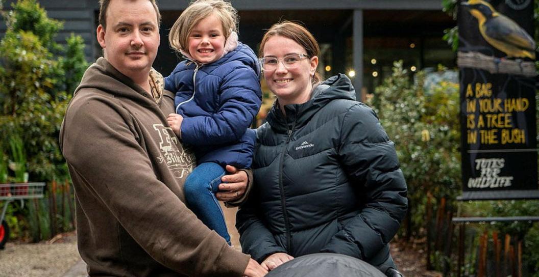 A man a woman and a toddler posing for the camera with a pram