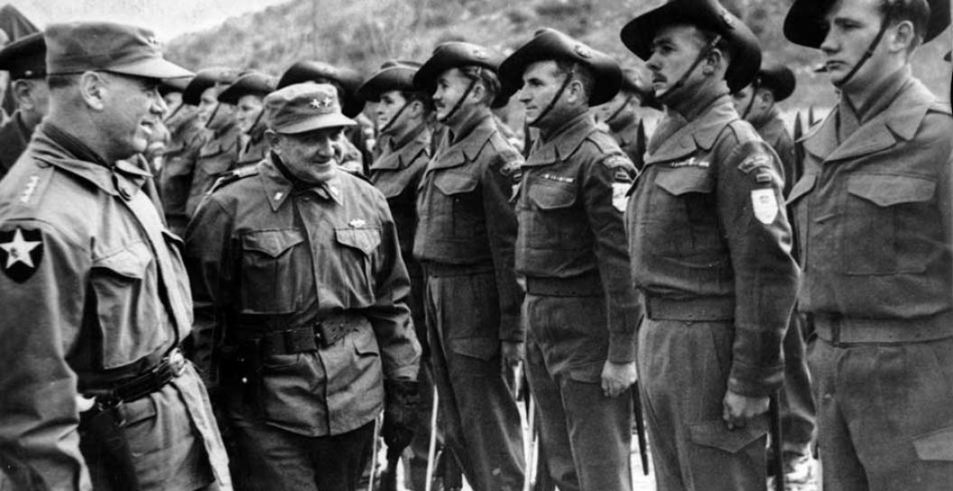 Two generals inspect a line of soldiers in slouch hats standing at attention