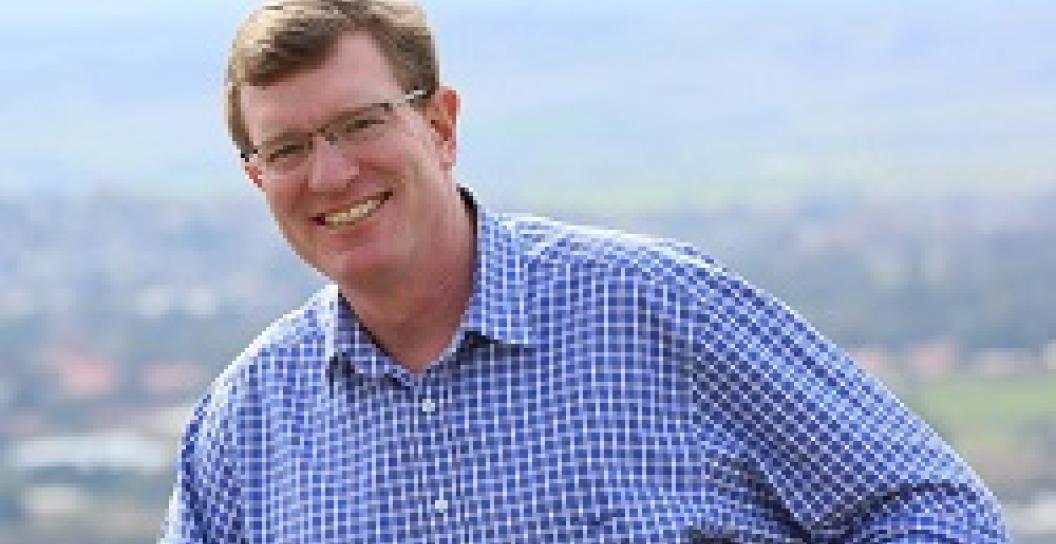 Smiling middle-aged man wearing check shirt with countryside in background