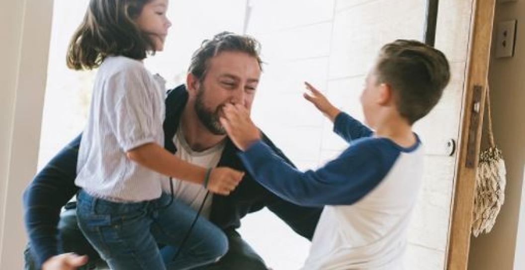 Two children jump into the arms of man