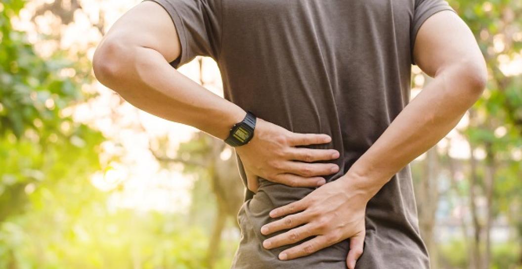 Photo of man with his hands on his own back